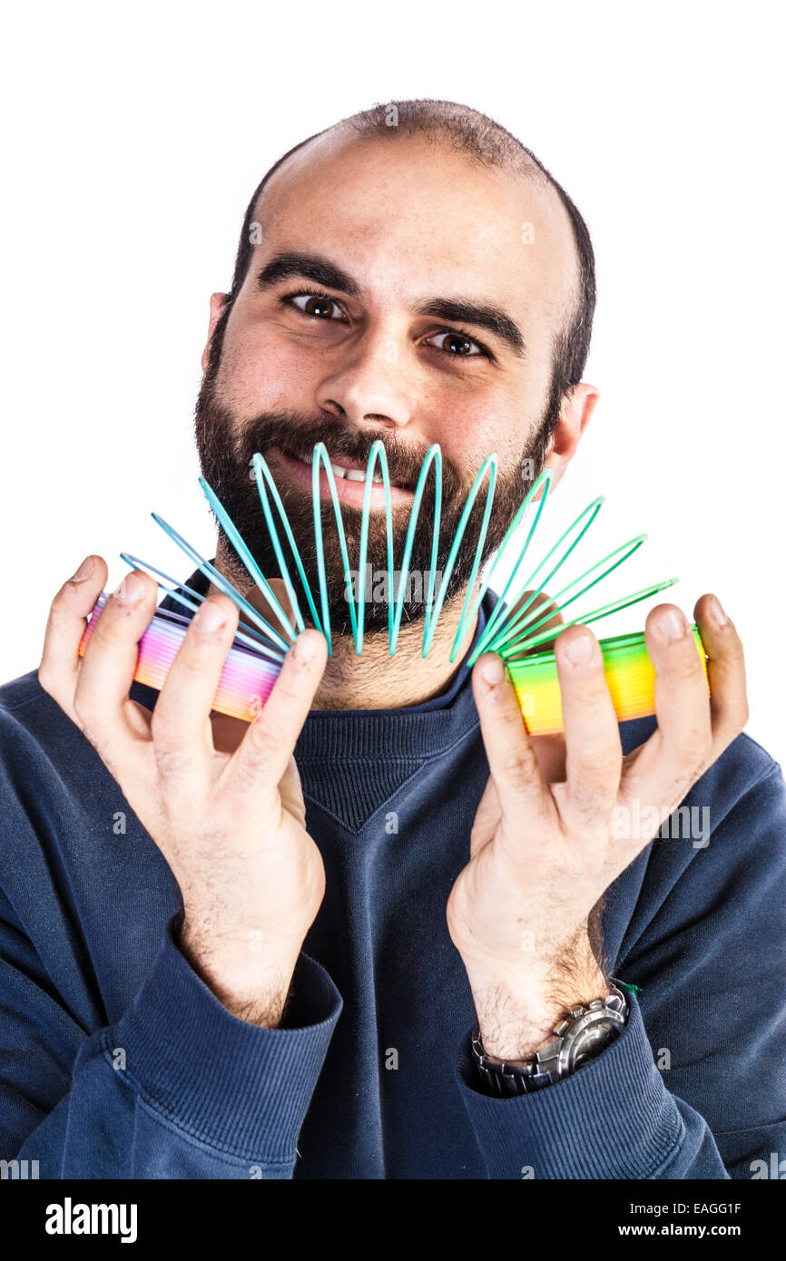 a bearded man playing with a rainbow slinky toy and looking silly Stock Photo