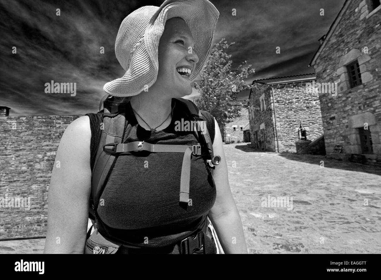 Spain, Galicia: Happy pilgrim girl arriving after exhausted walk in the medieval village O Cebreiro as black and white version Stock Photo