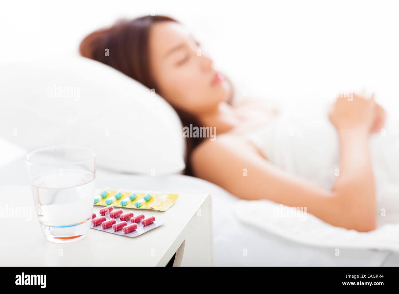 medicines and water in front, woman caught cold sleeping in bed Stock Photo