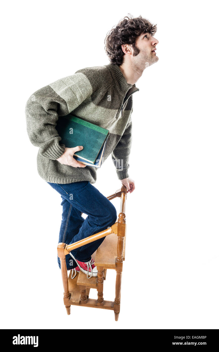 an handsome guy, maybe a student, in casual clothing clambering on a small wooden library ladder. isolated on white Stock Photo