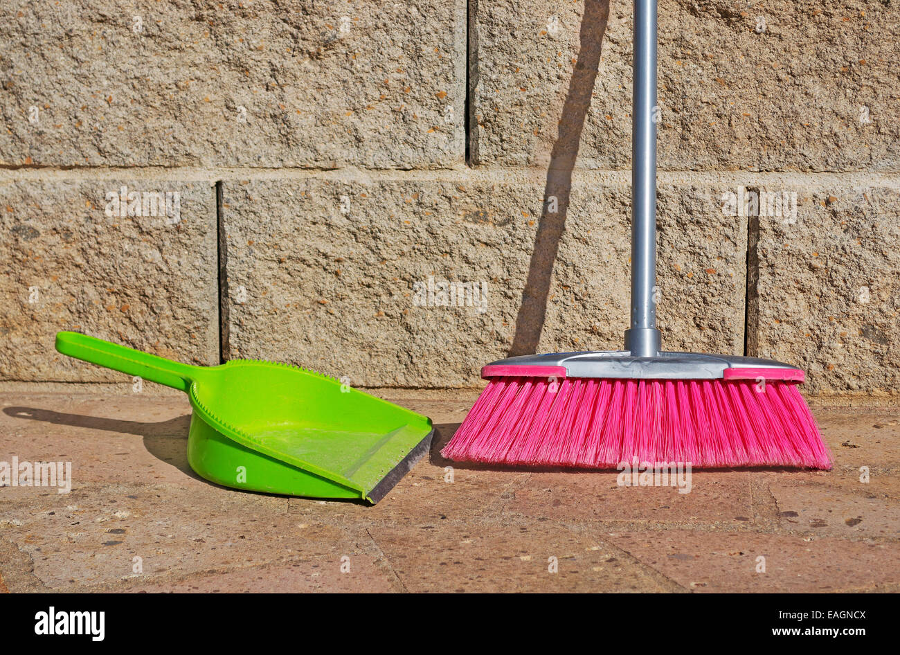 green shovel and pink broom on the ground Stock Photo