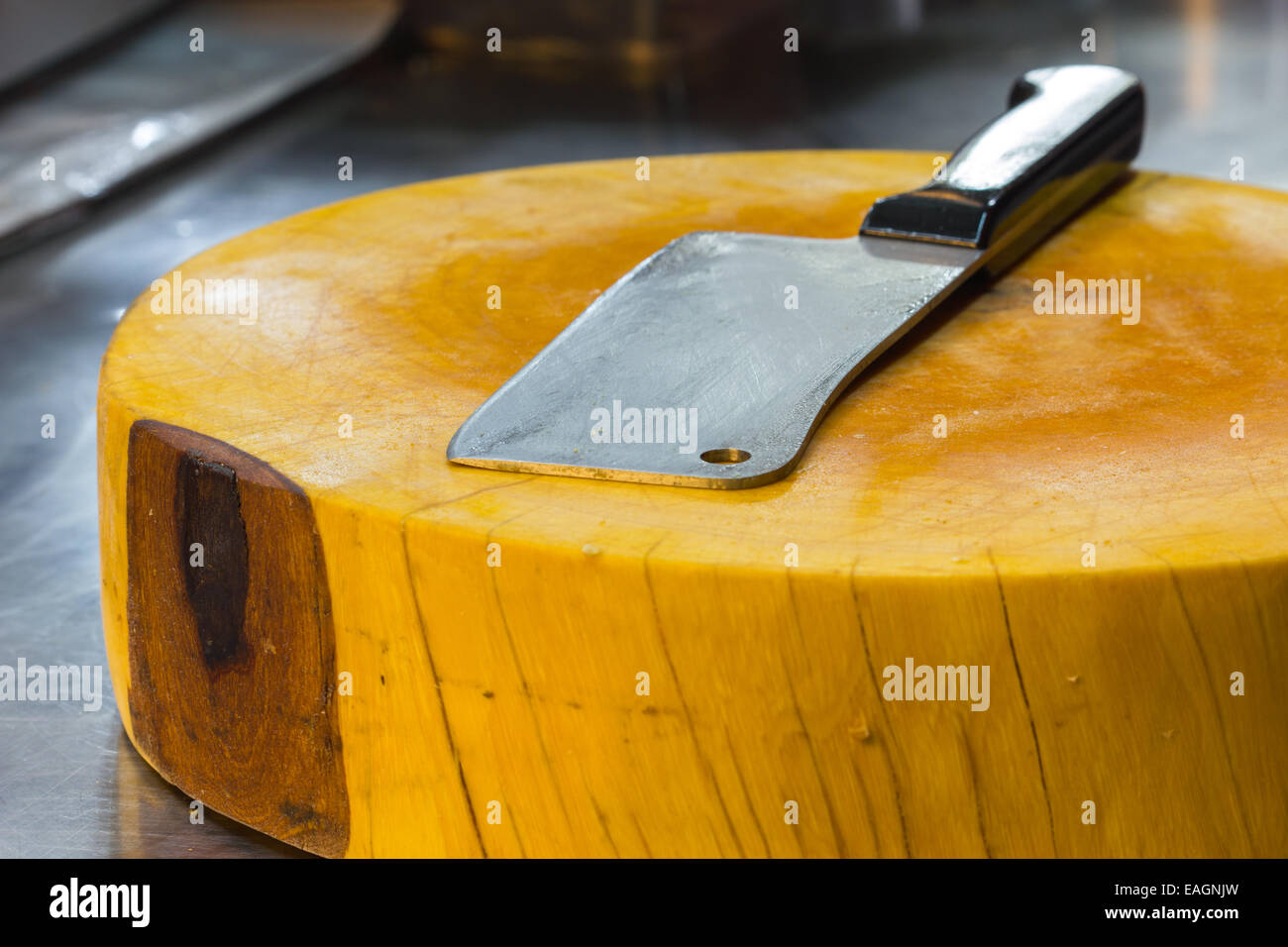 cleaver on yellow big chopping block in sidewalk restaurant in thailand Stock Photo