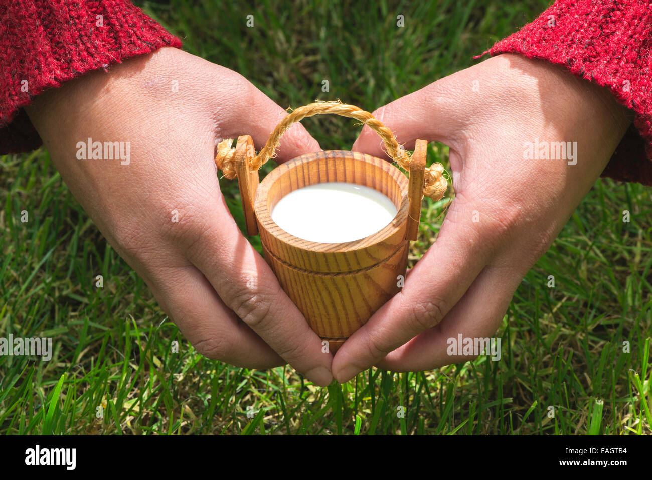 Women hold small wooden mug of milk Stock Photo