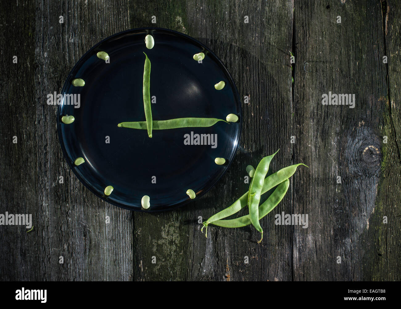 Bean pods and green beans in black plate. Clock conception Stock Photo ...