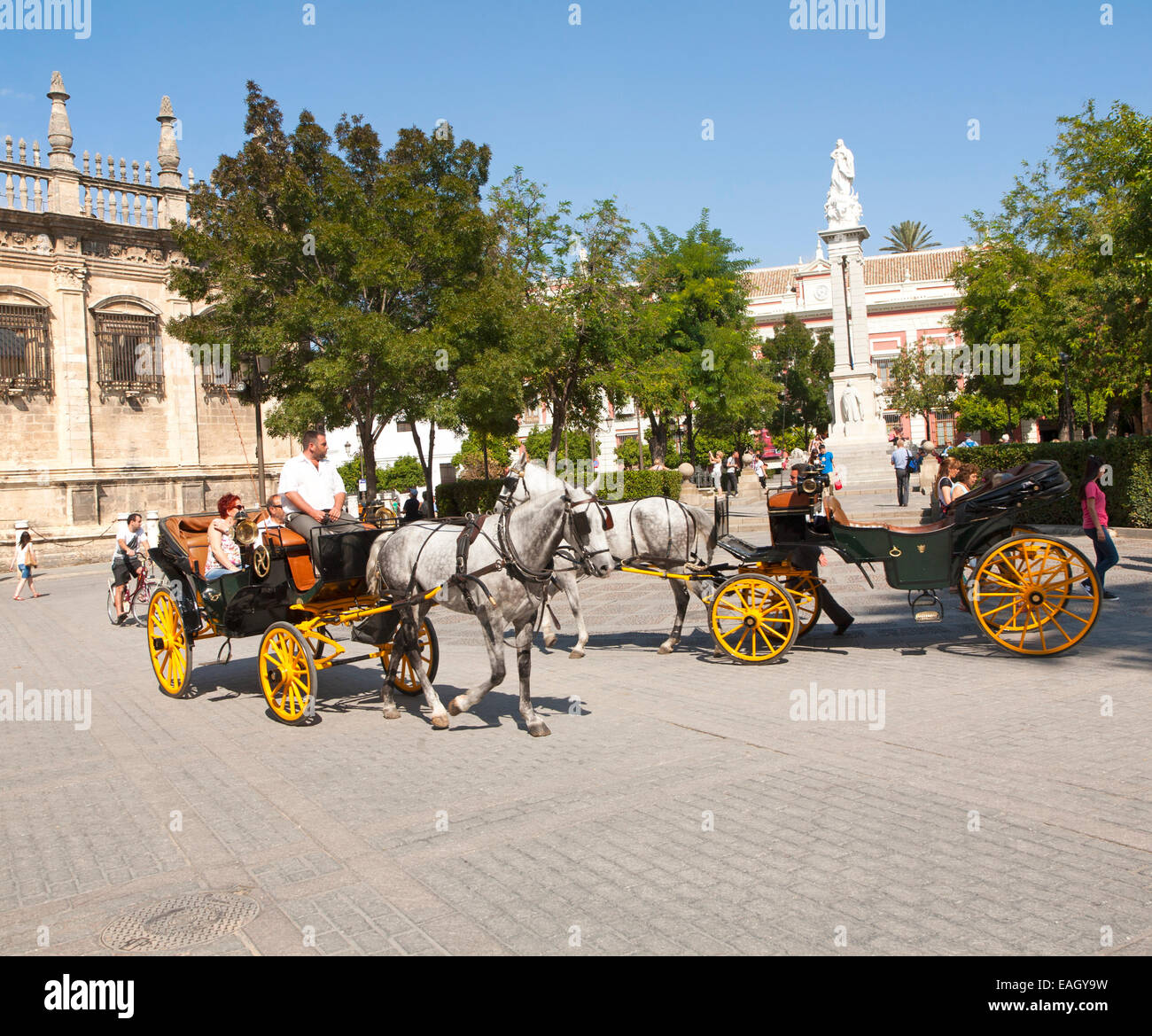 Horse and carriage rides for tourists through the historic central areas in Plaza del Triunfo, Seville, Spain Stock Photo