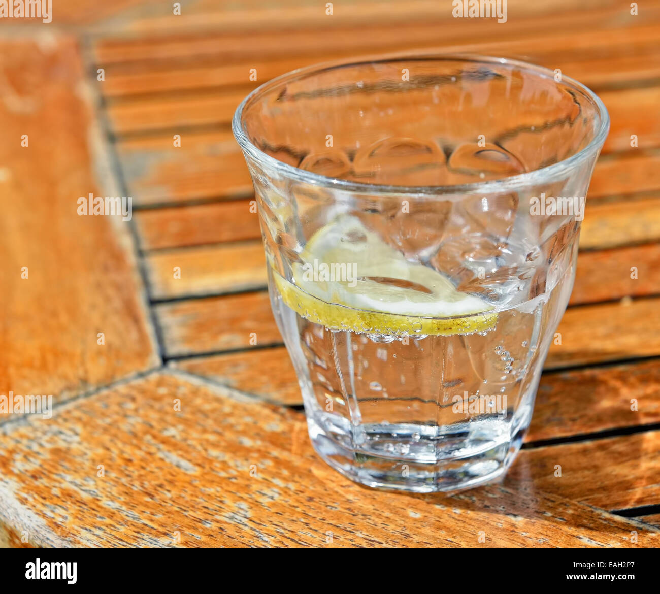Glass with sparkling water, ice cubes and a slice of a lemon on a ...