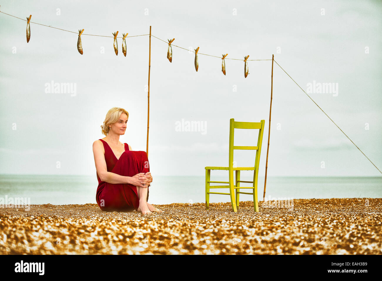 Woman beach dress chair shingle gold green washing line Stock Photo