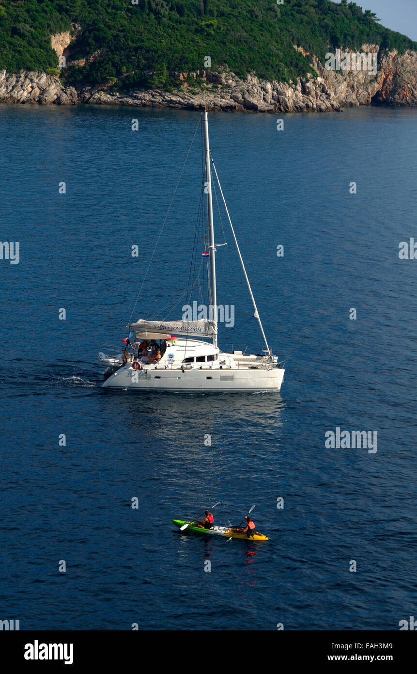 UK registered catamaran sailing yacht cruiser motoring in Croatia. Canoeists in foreground