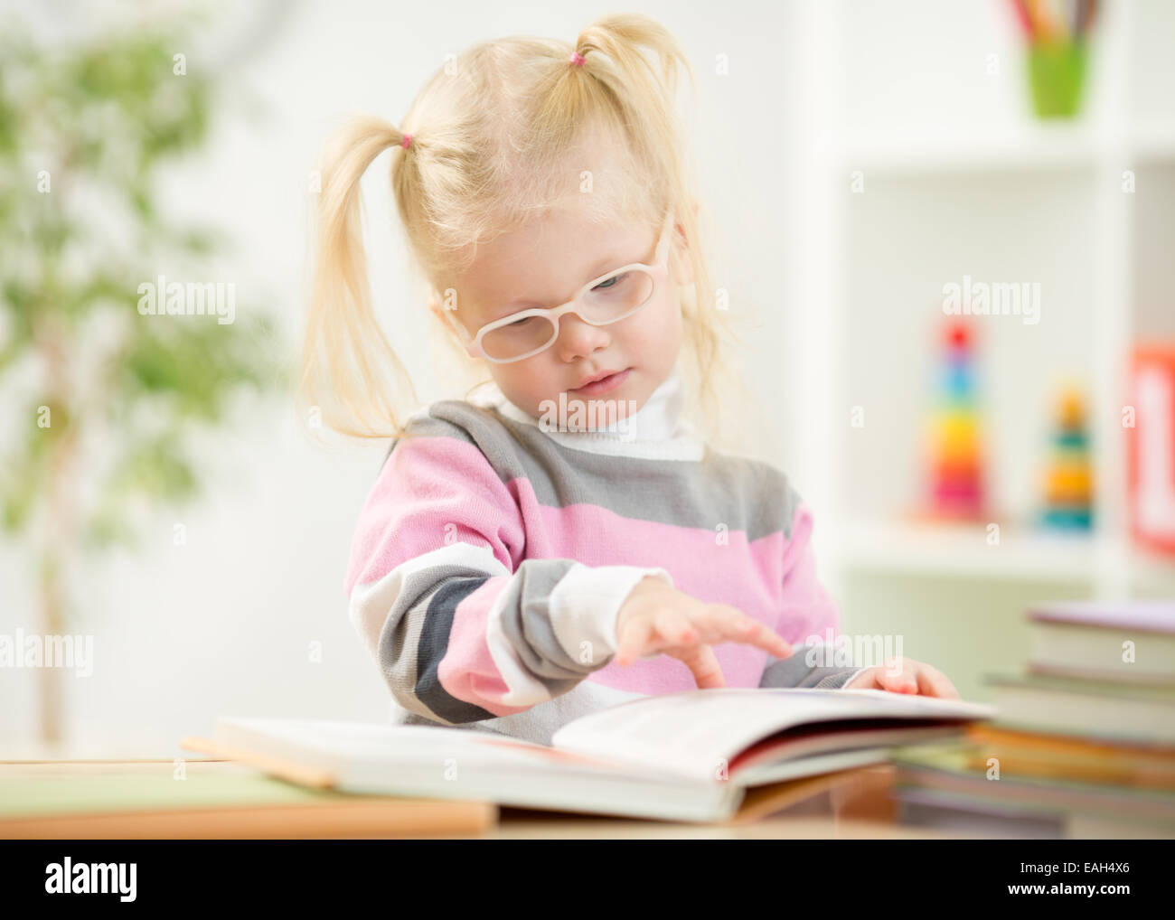 Funny kid in eyeglases reading book at home Stock Photo
