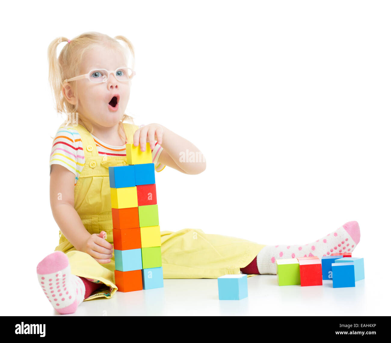 Funny kid in eyeglases making tower using blocks with letters isolated Stock Photo