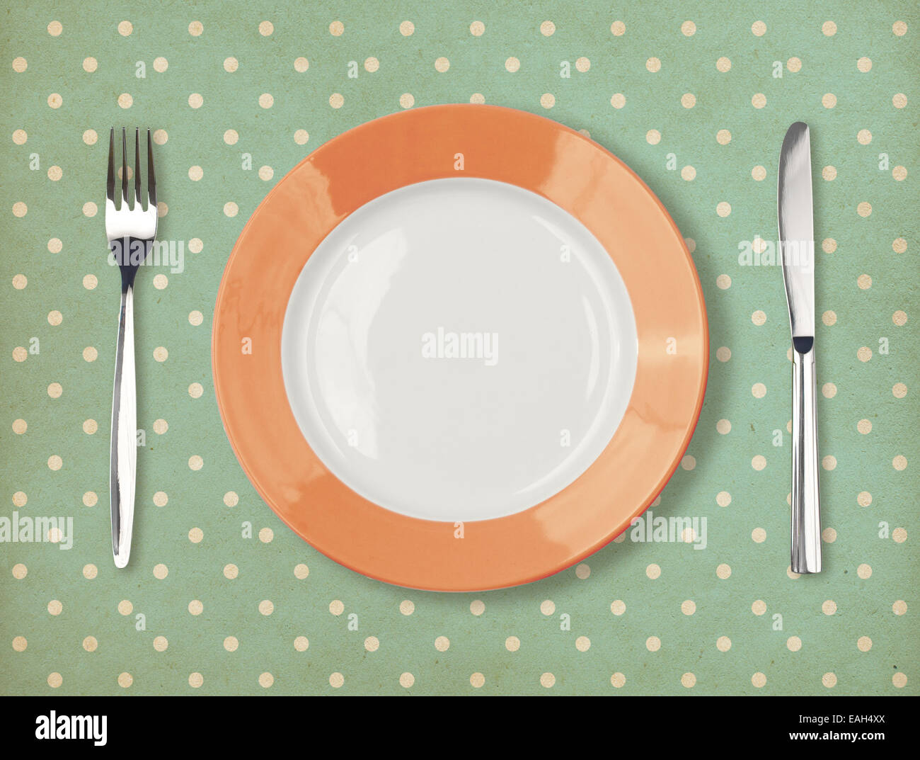 Retro plate with fork and knife on polka dot background Stock Photo