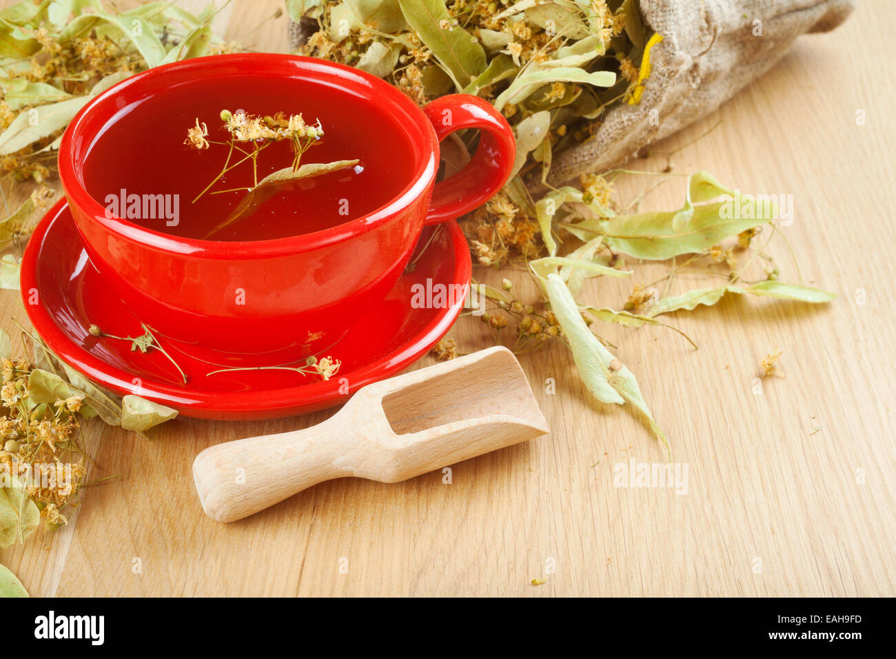 cup of linden tea and flowers in canvas bag on wooden table Stock Photo
