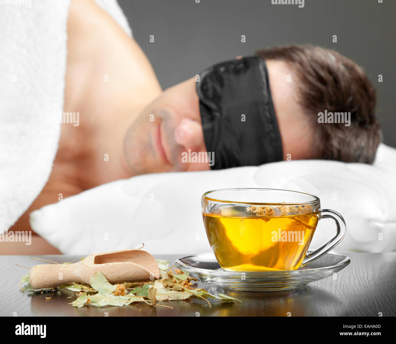 Man with Sleeping mask sleep on a bed, cup of herbal tea in the