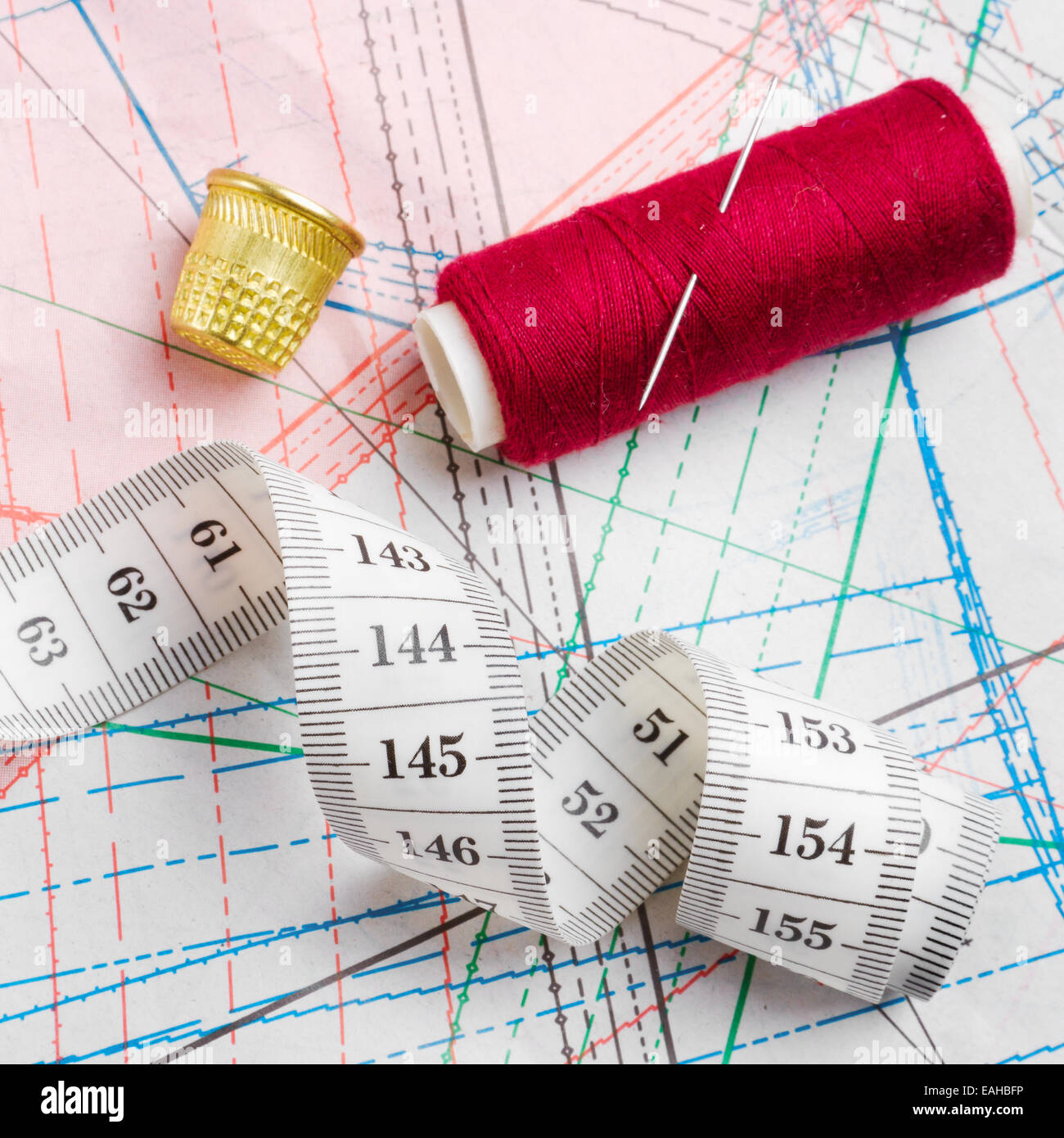 https://c8.alamy.com/comp/EAHBFP/measuring-tape-thimble-and-bobbin-of-thread-lie-of-paper-patterns-EAHBFP.jpg