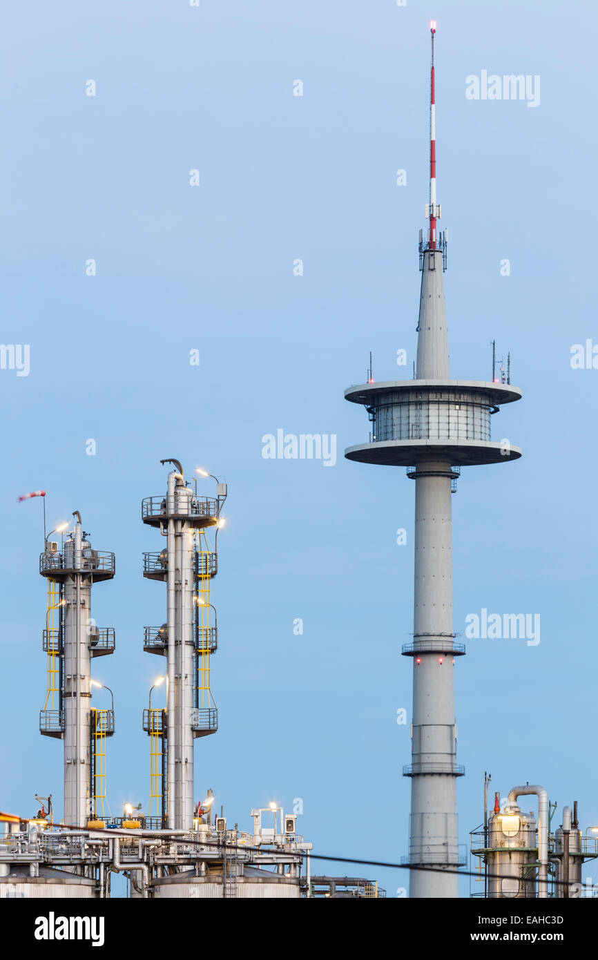 Distillation towers in a chemical plant and a communications tower in the background with night blue sky. Stock Photo