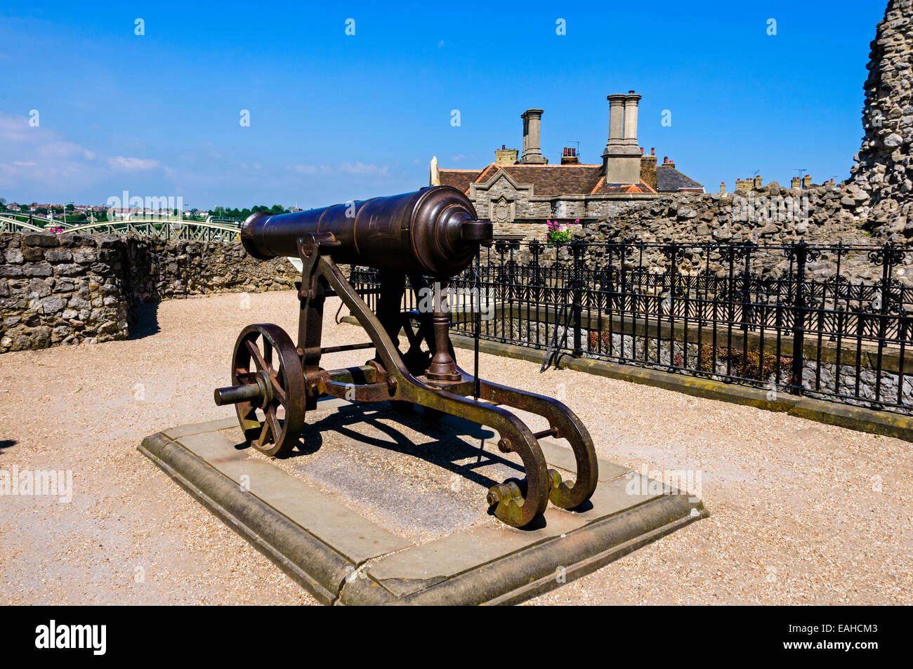 A black cast iron cannon mounted on its carriage in the grounds of Rochester castle protected by the ruins of the curtain wall,. Stock Photo