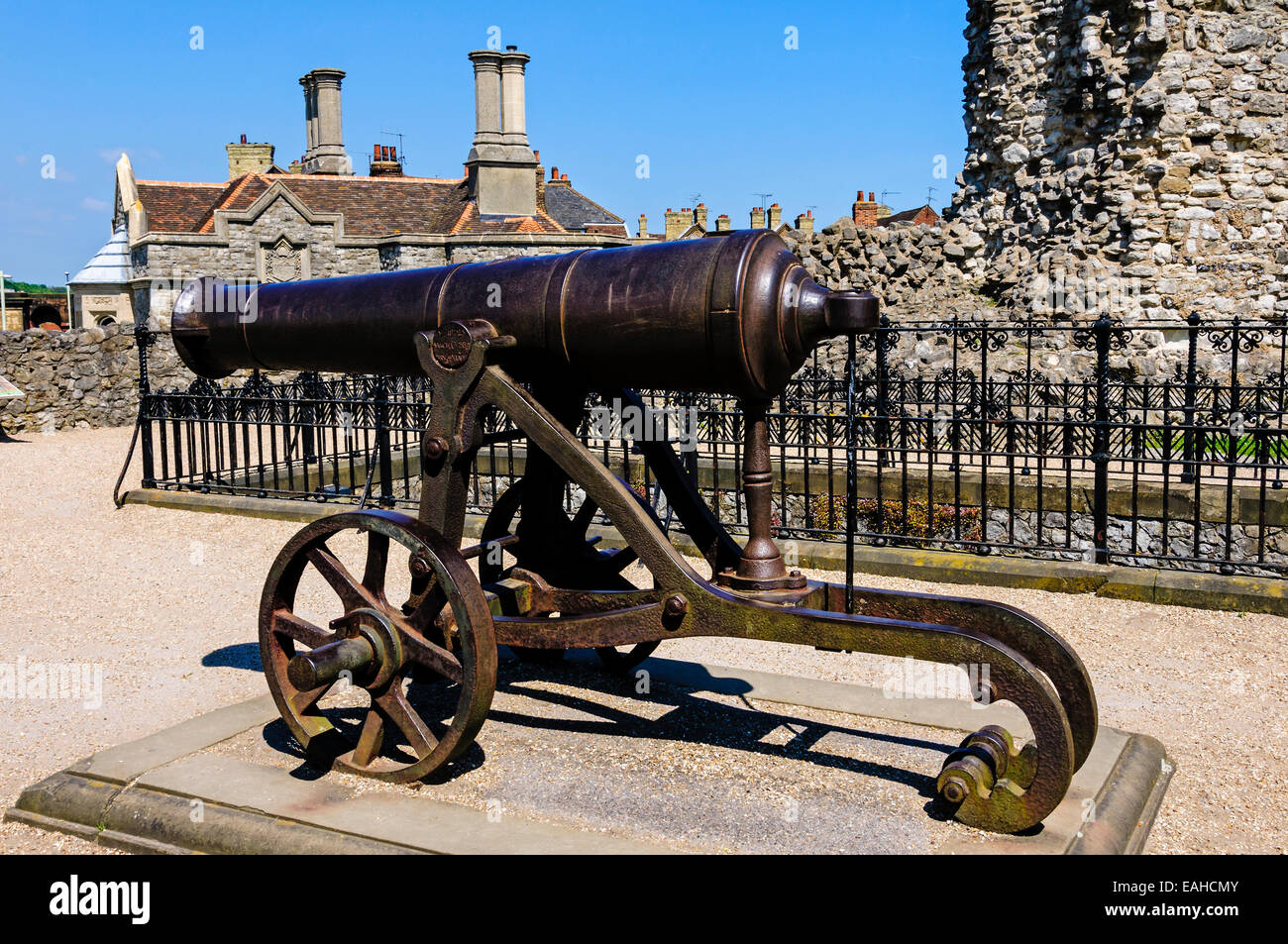 A black cast iron cannon mounted on its carriage in the grounds of Rochester castle protected by the ruins of the curtain wall,. Stock Photo