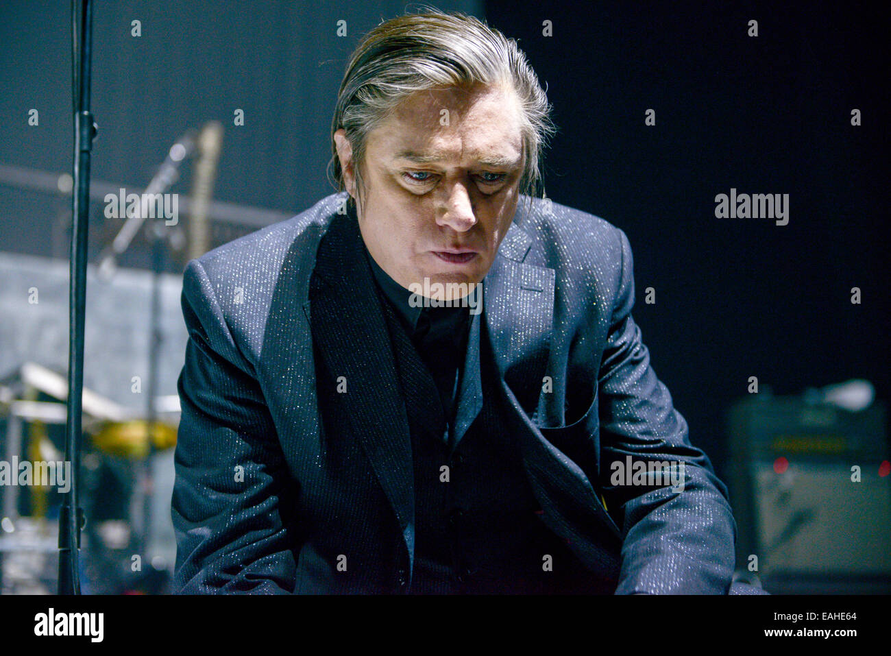 Blixa Bargeld, singer of the German band 'Einstuerzende Neubauten,' kneels on the edge of the stage during the concert in Tempodrom in Berlin, Germany, 11 November 2014. Their new album 'Lament,' which is deals with World War I, came out on 07 November 2014. Photo: Jason Harrell/dpa NO WIRE SERVICE Stock Photo