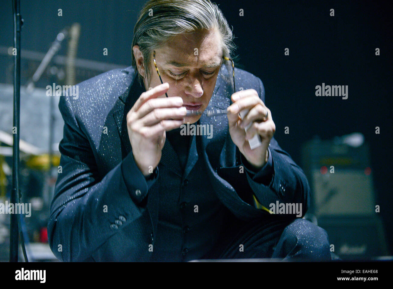 Blixa Bargeld, singer of the German band 'Einstuerzende Neubauten,' takes off his reading glasses after glancing at the set list on the edge of the stage during the concert in Tempodrom in Berlin, Germany, 11 November 2014. Their new album 'Lament,' which is deals with World War I, came out on 07 November 2014. Photo: Jason Harrell/dpa NO WIRE SERVICE Stock Photo