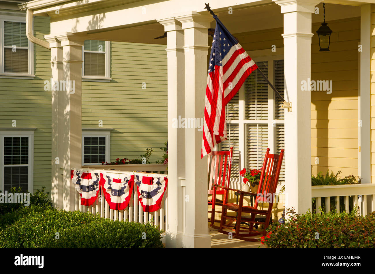 An American Flag and buntings hang from a front porch of an upscale, Victorian home in celebration of the upcoming holiday Stock Photo