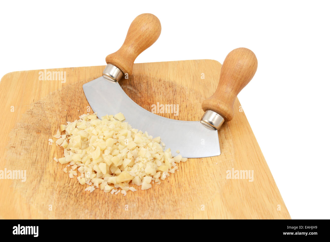 Finely chopped macadamia nuts with a rocking knife on a wooden chopping board, isolated on a white background Stock Photo