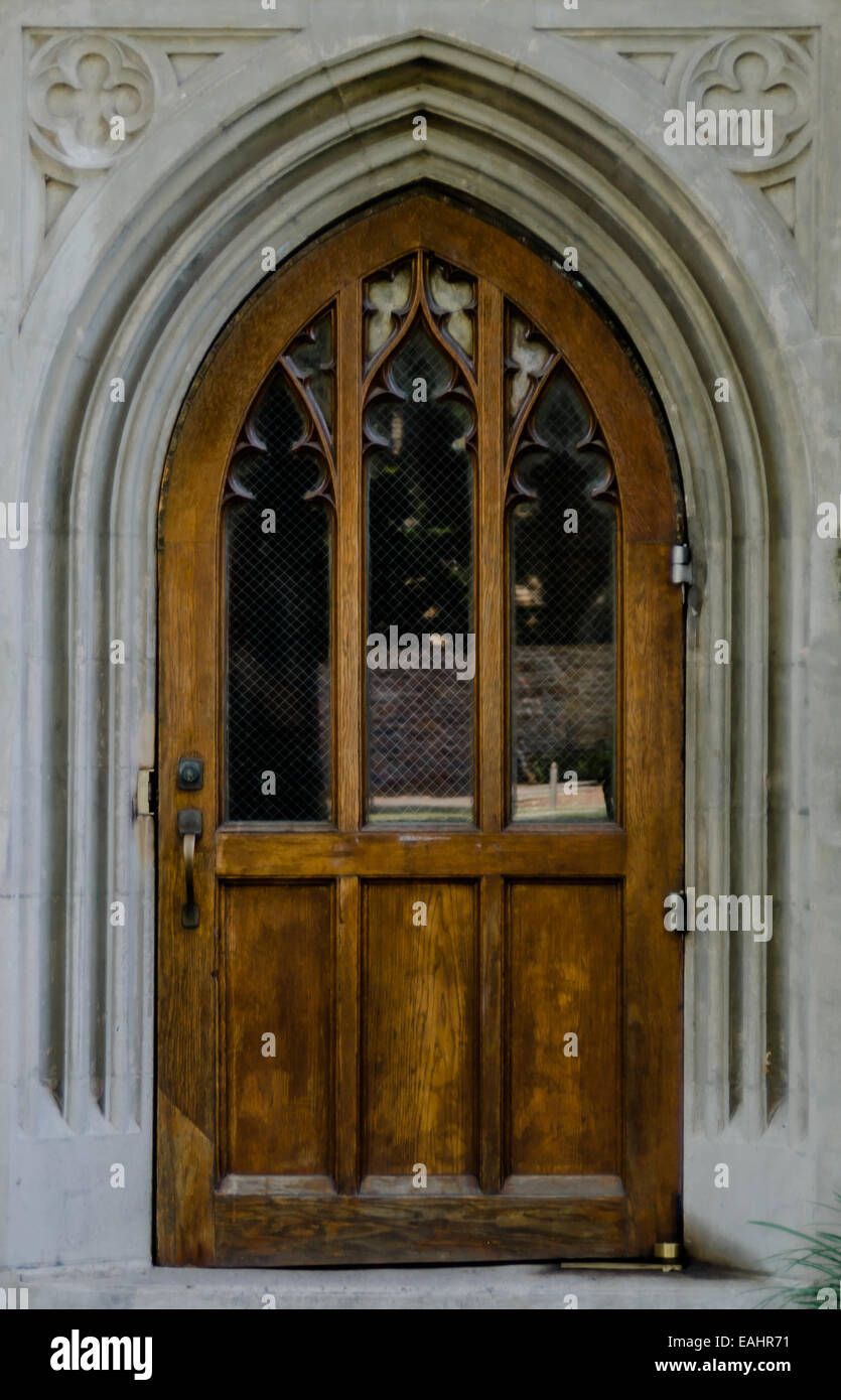A large wooden door provides an entry to a gothic chapel Stock Photo
