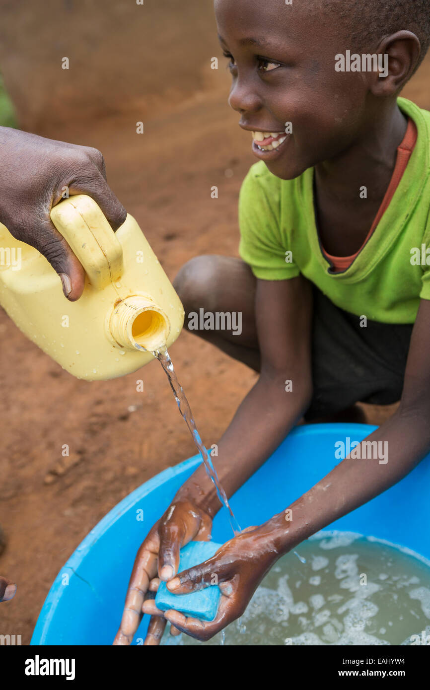 A boy washes his hands with the help of a community worker - Bukwo District, Uganda, East Africa. Stock Photo