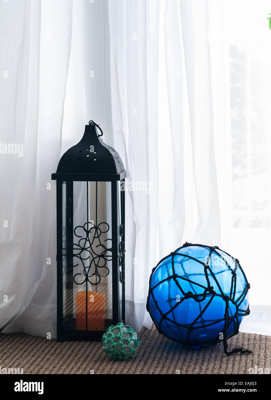 Hurricane lantern in front of sheer curtain backlit by the sun Stock Photo