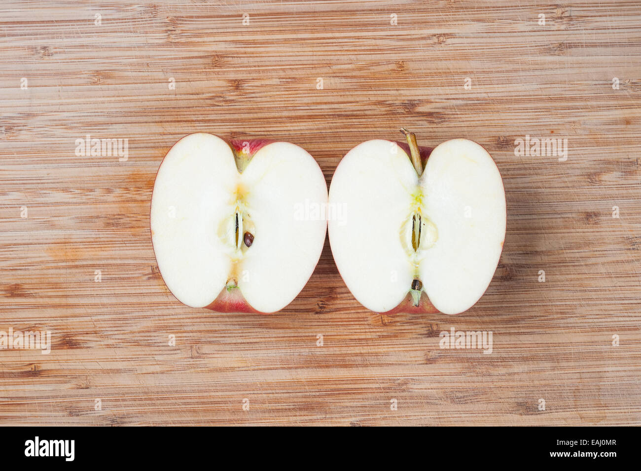 Apple sliced in half on a cutting board Stock Photo