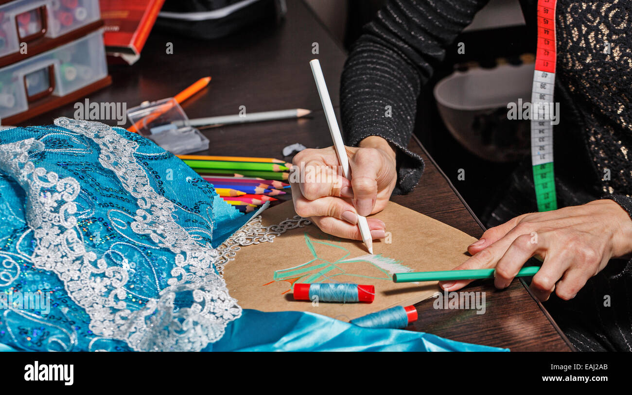 Fashion designer draws a sketch of the future dress on paper, beside ...