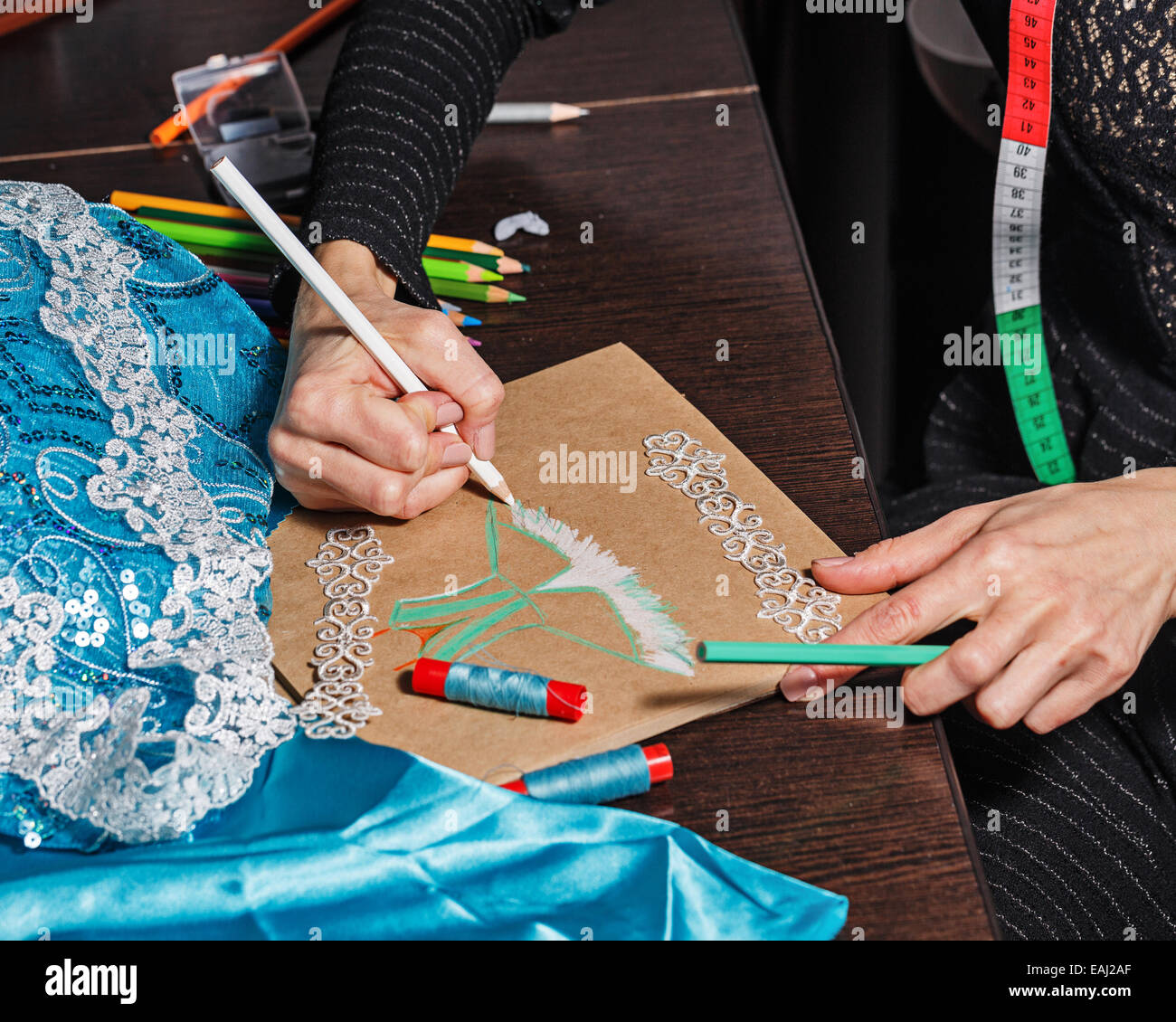 Fashion designer draws a sketch of the future dress on paper, beside ...