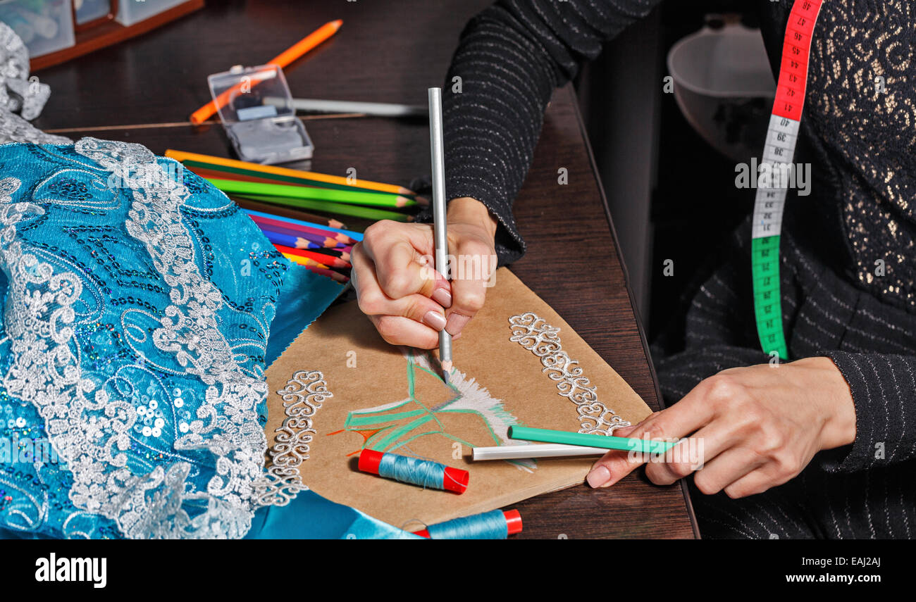 Fashion designer draws a sketch of the future dress on paper, beside ...