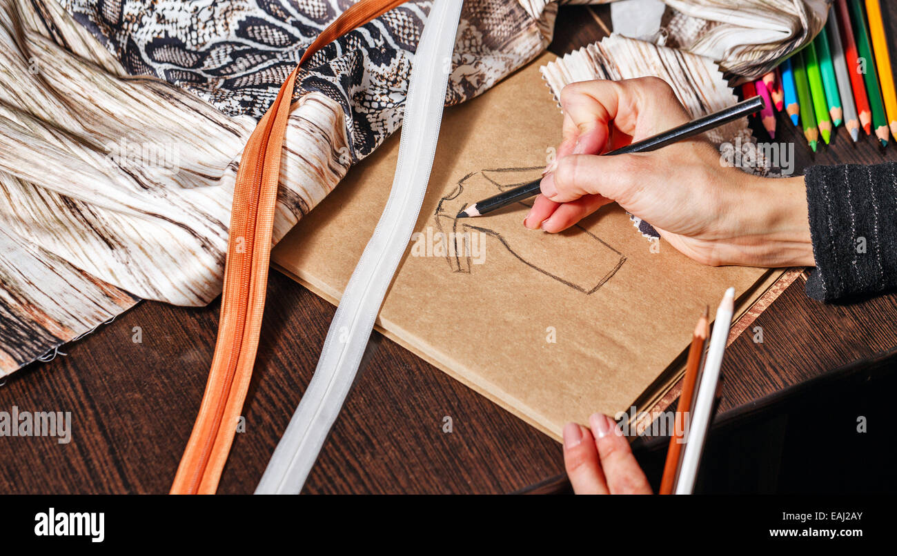 Fashion designer draws a sketch of the future dress on paper, beside ...