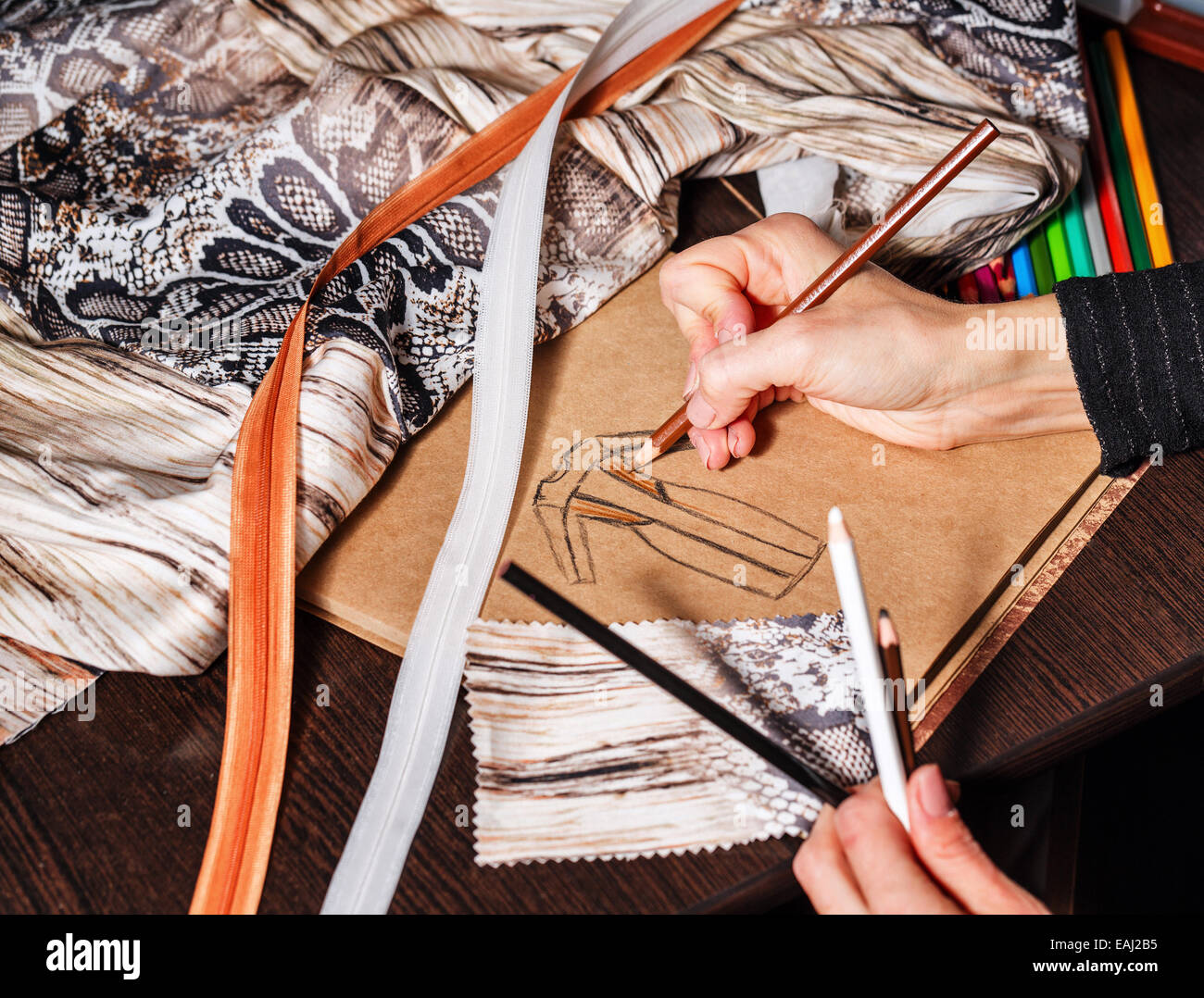 Fashion designer draws a sketch of the future dress on paper, beside ...