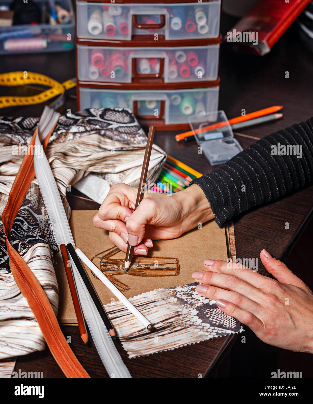 Fashion designer draws a sketch of the future dress on paper, beside ...
