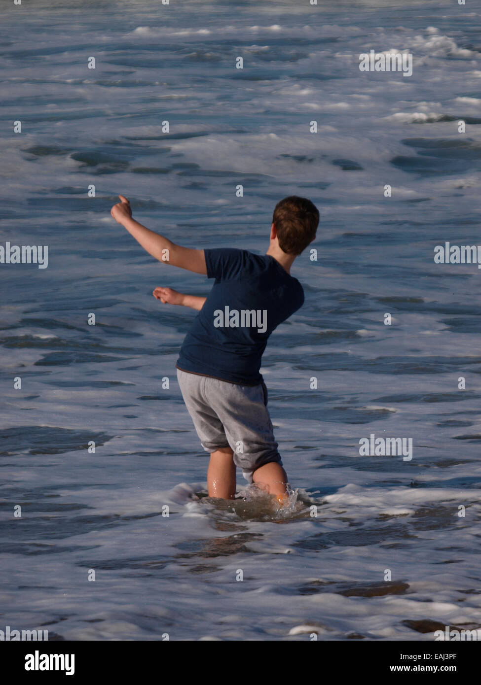 Boy skimming stones in the sea, Bude, Cornwall, UK Stock Photo