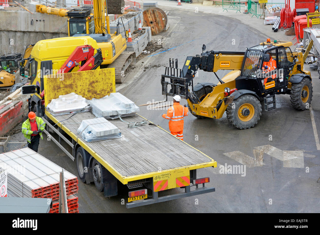 Aerial view building construction site forklift truck to unload flatbed delivery lorry workmen wearing hard hat & high visibility jacket London UK Stock Photo