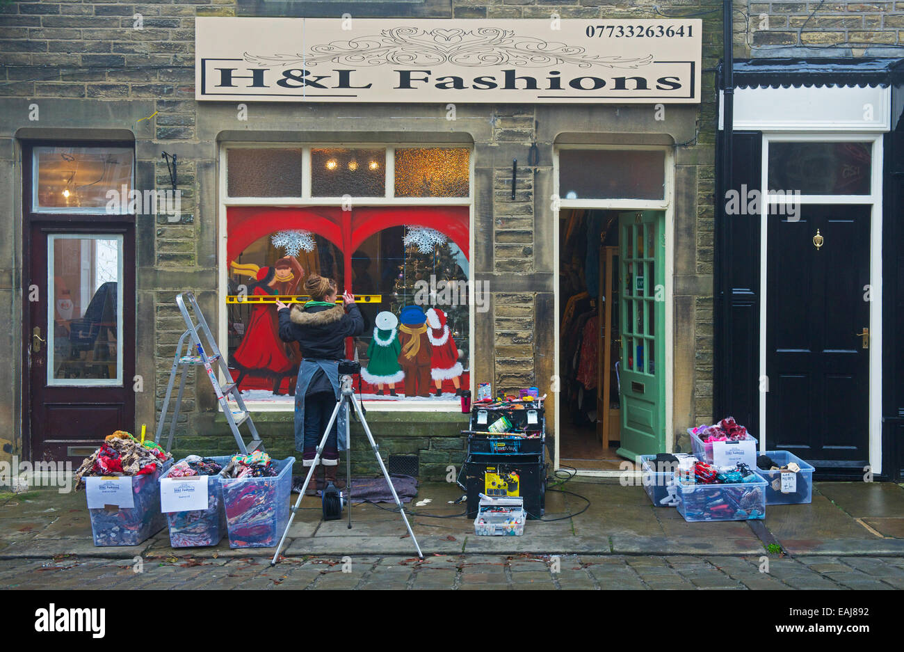 Jenny Froglet, window painter, working on a shop window in Haworth, West Yorkshire, England UK Stock Photo