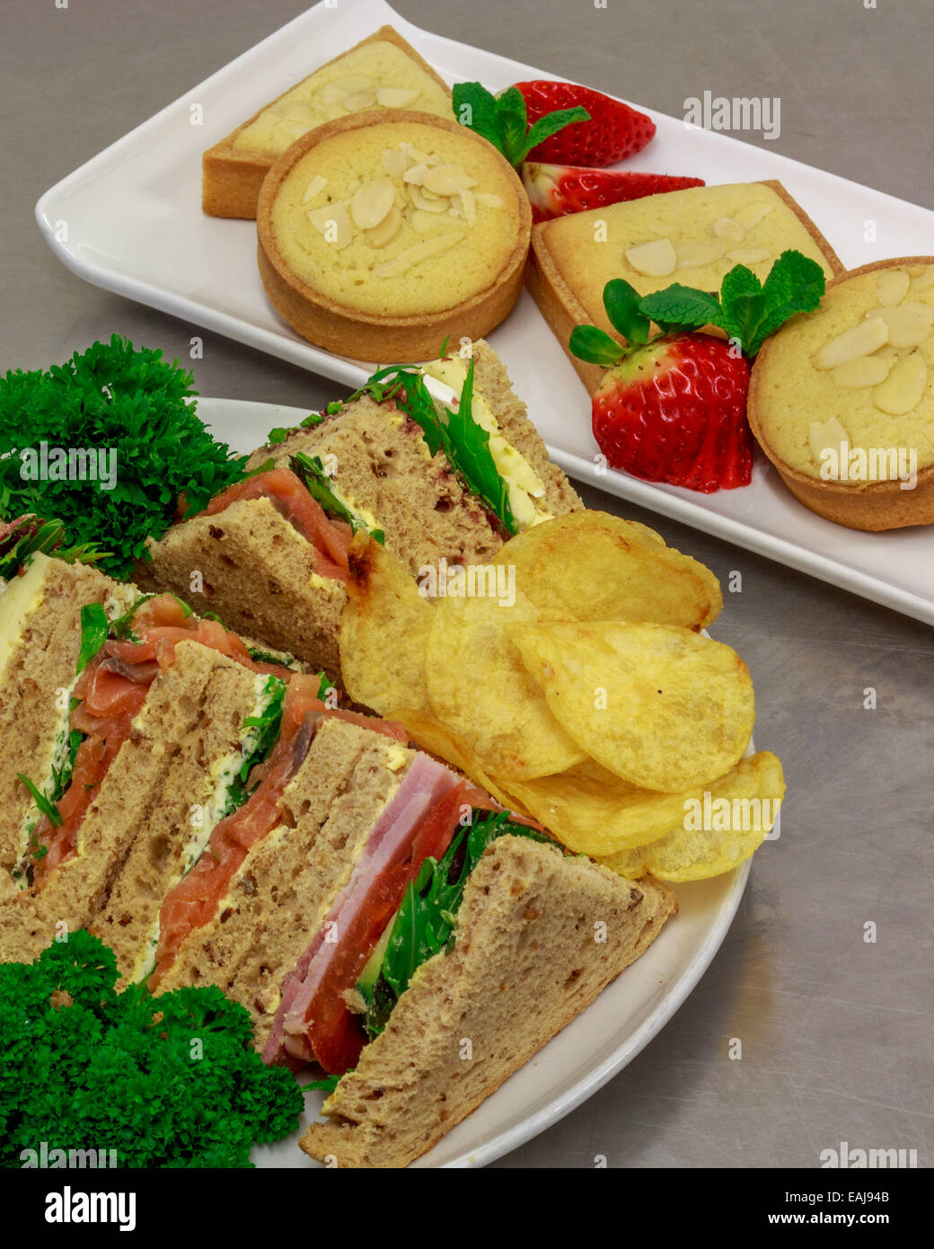 plated buffet lunch with a selection of sandwiches fruit baked sweets and crisps Stock Photo Alamy