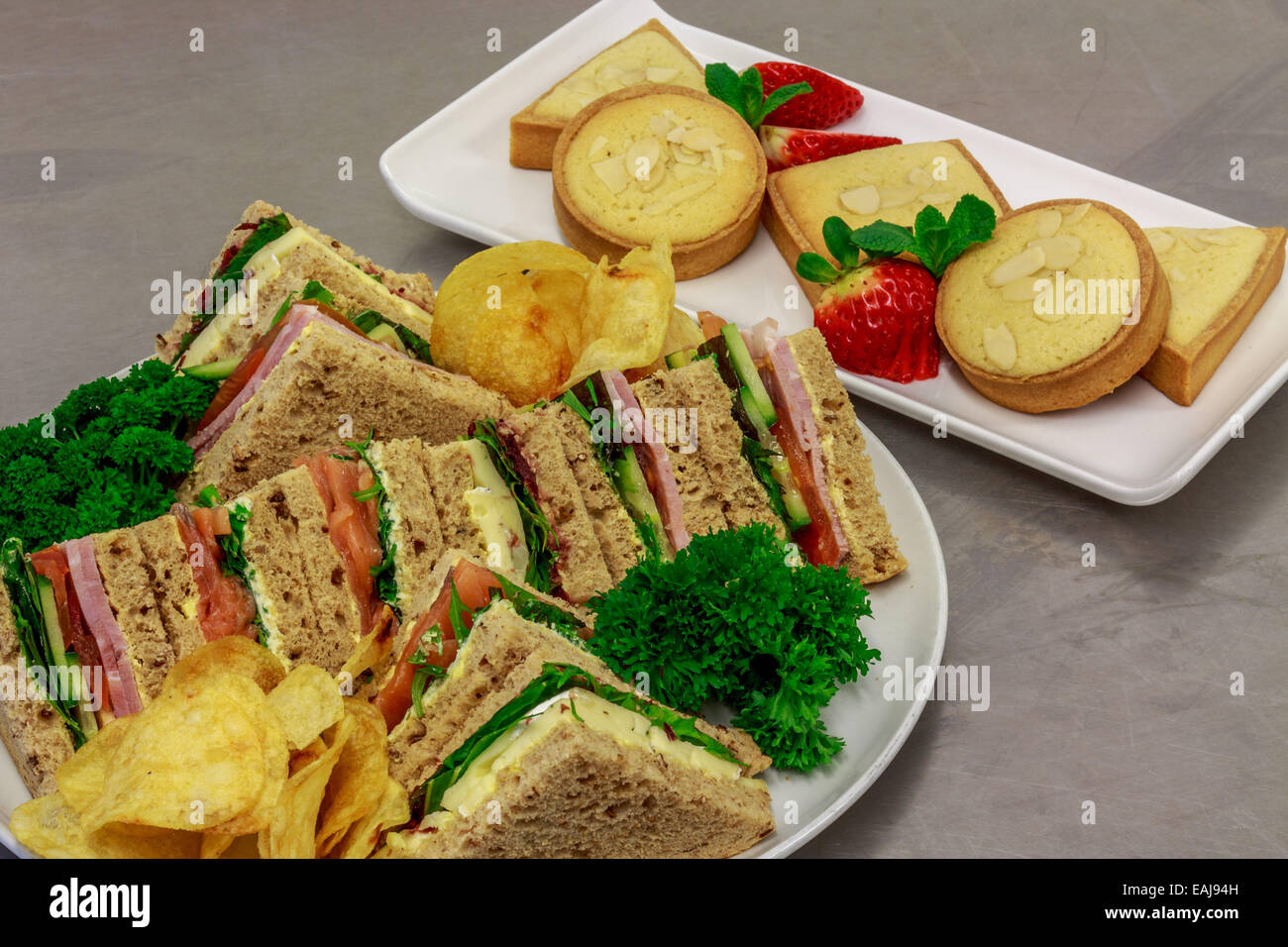 plated buffet lunch with a selection of sandwiches fruit baked sweets and crisps Stock Photo Alamy