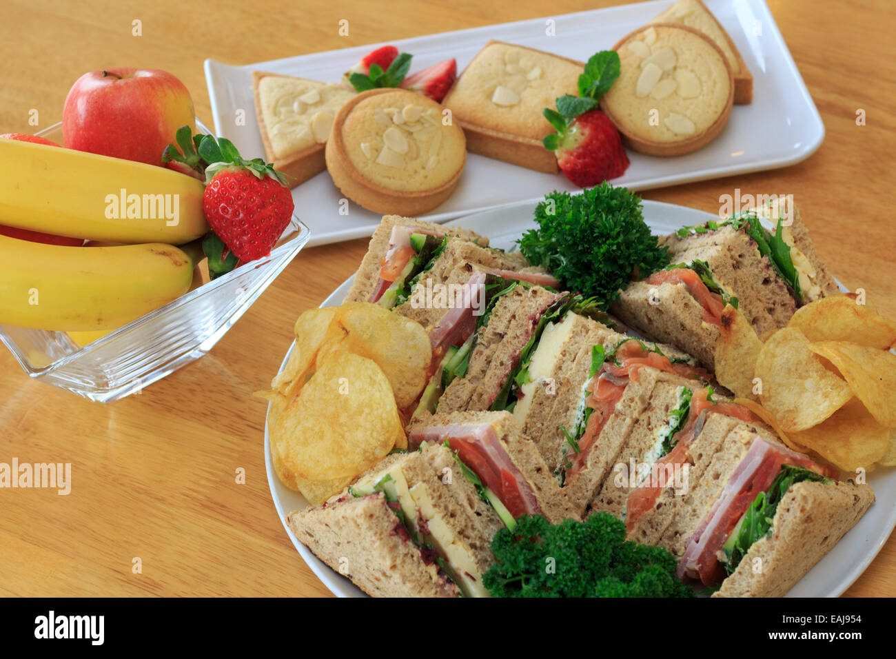 plated buffet lunch with a selection of sandwiches fruit baked sweets and crisps Stock Photo Alamy