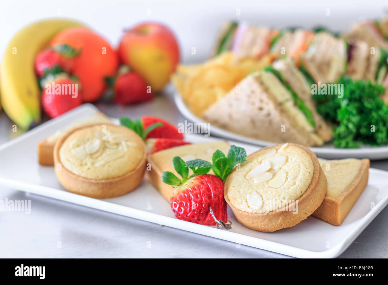 plated buffet lunch with a selection of sandwiches fruit baked sweets and crisps Stock Photo Alamy