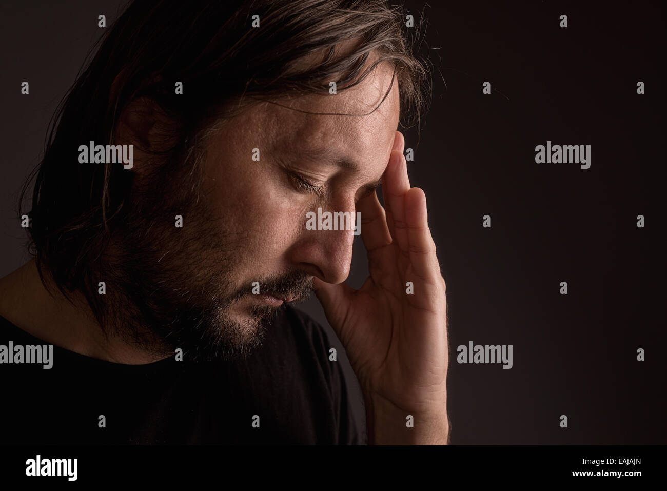 Bearded adult man with migraine headache, low key portrait Stock Photo