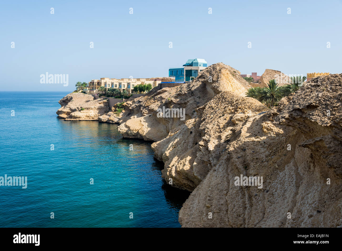 Luxury hotel rooms and apartments on top of limestone cliff by Arabian Sea. Oman. Stock Photo