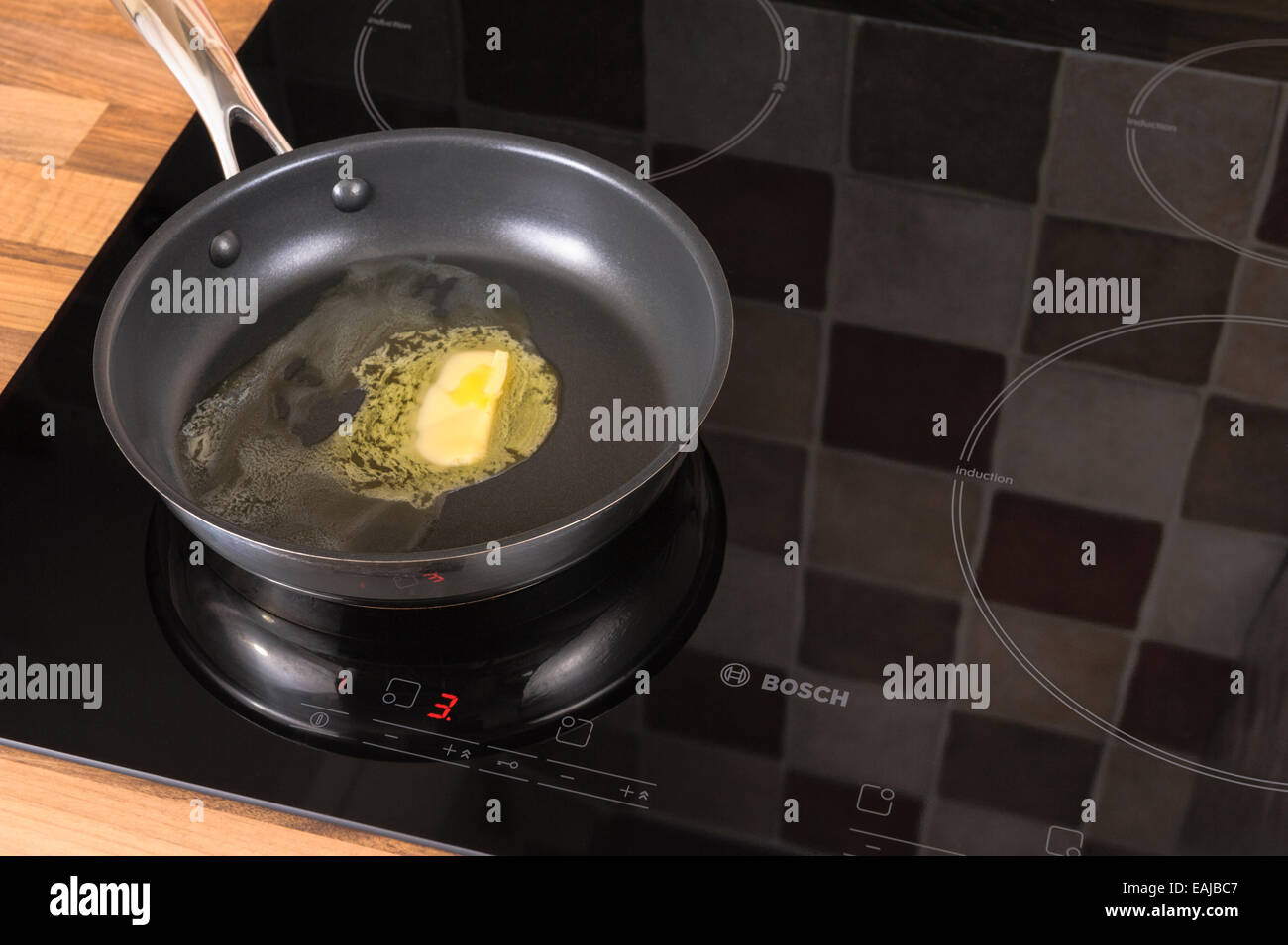 Butter melting in a frying pan, on an induction hob.Unhealthy, cholestrol. Stock Photo