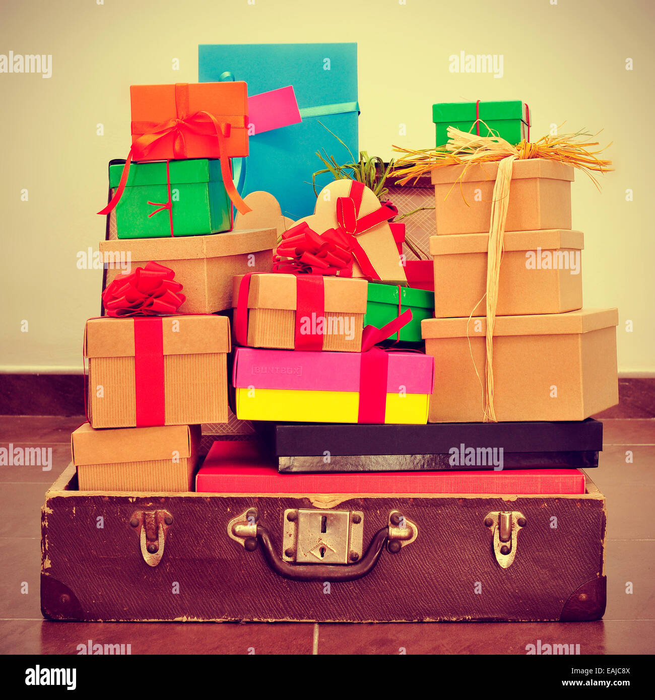 a pile of gifts of different colors and sizes in an old suitcase, with a retro effect Stock Photo