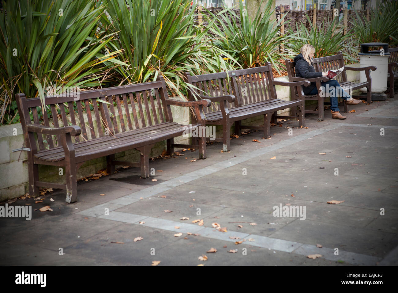 Solitary adult woman sitting alone with head in hands sitting on bench by herself, Southport, Merseyside,UK Stock Photo