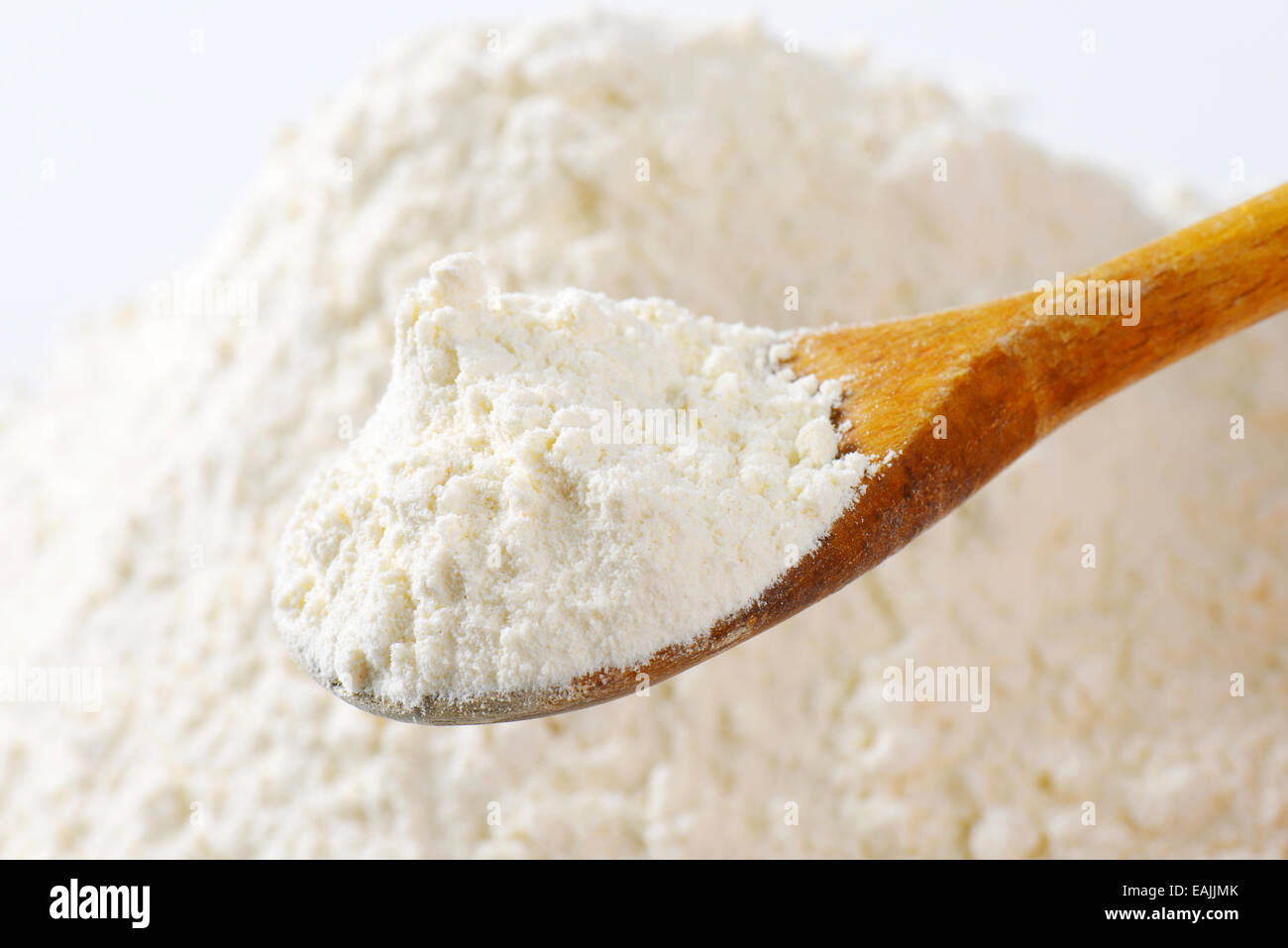 Pile of finely ground flour and wooden spoon Stock Photo