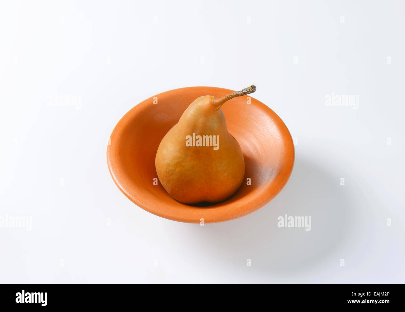 Ripe Bosc pear in a terracotta bowl Stock Photo