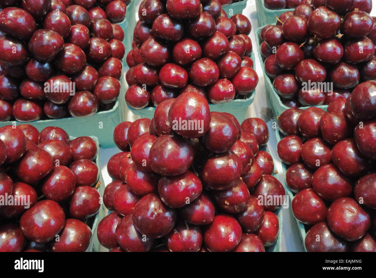 Cherries displayed in green cartons at market Stock Photo